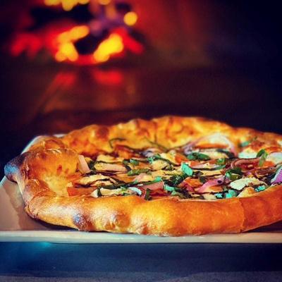 Wood-fired pizza with fresh basil and melted cheese.