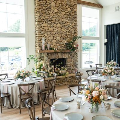Elegant dining area with round tables set for an event and a stone fireplace