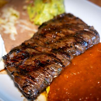 Grilled steak served with refried beans and sauce.