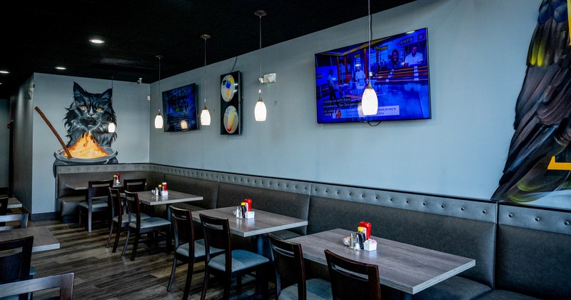 Diner tables, chairs, tv screens on the wall above