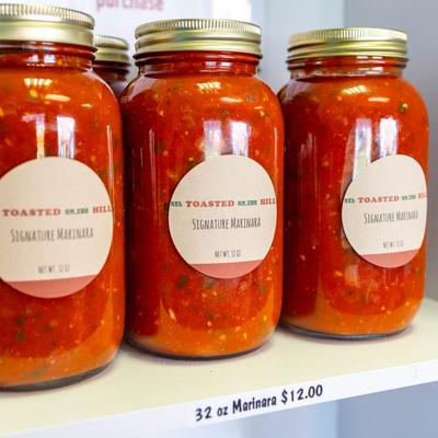 Jars of marinara on a white shelf.