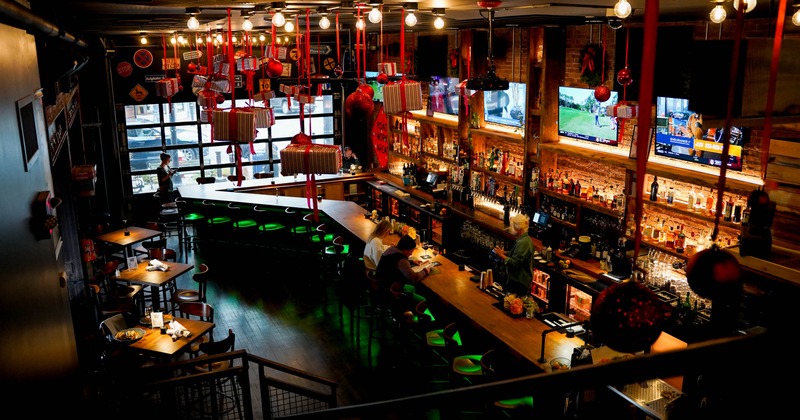 Warmly lit bar interior with hanging ornaments and a large wooden counter