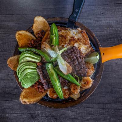 Grilled steak, chicken, and shrimp on a skillet, top view.
