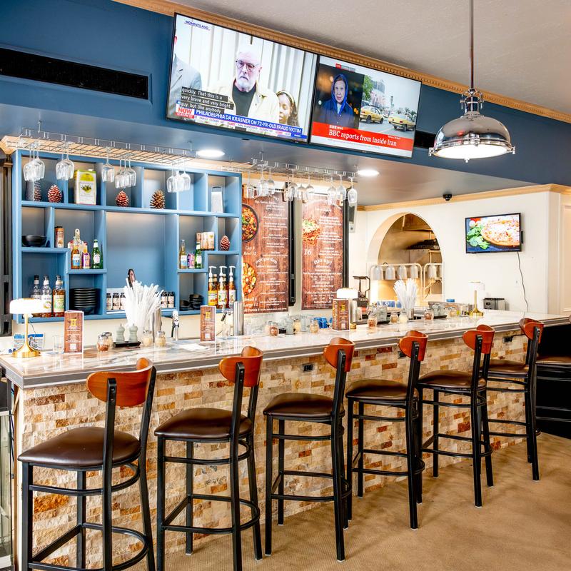 A modern restaurant bar area with a marble counter, wooden stools