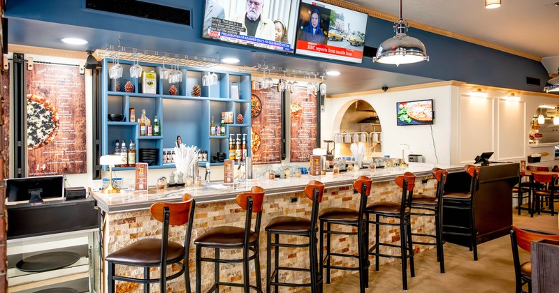 A modern restaurant bar area with a marble counter, wooden stools