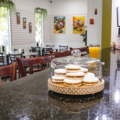 Powdered pastries displayed beneath a glass dome on a granite counter.