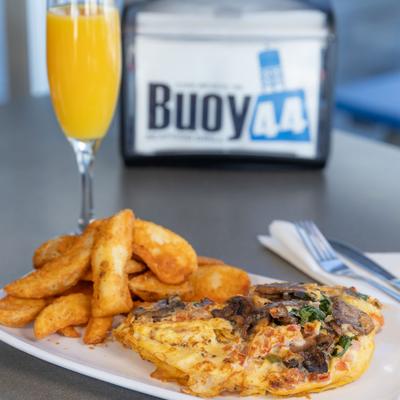 Veggie omelet served with thick cut potato wedges and a mimosa cocktail.