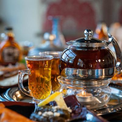 Glass teapot and cup with tea on a tray.