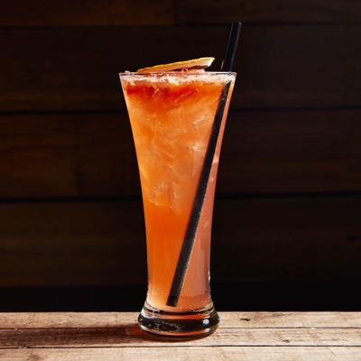 An orange cocktail drink decorated  with a dry citrus wheel.