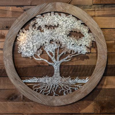 The White Oak Tavern metal tree logo mounted on a wooden wall.