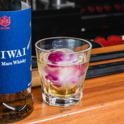 Bottle of Japanese Whisky and a glass containing the spirit over a large ice sphere.