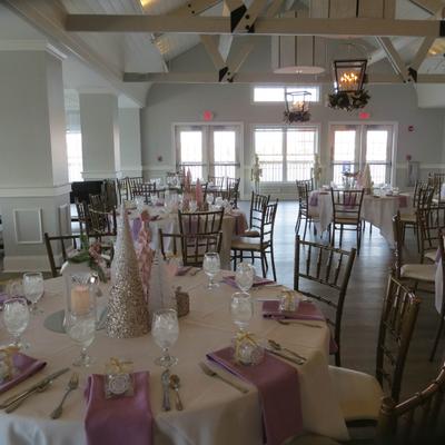 Fully set tables with pink napkins, glasses, and utensils.