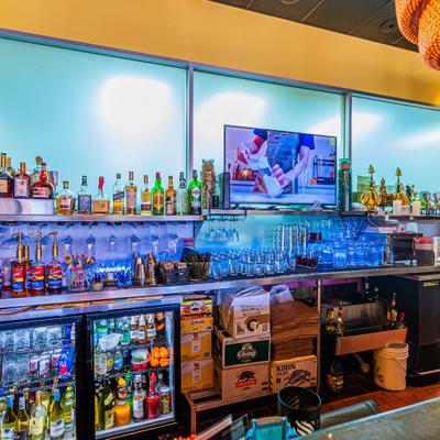 Bar area with bottle shelves behind a counter and a refrigerated display case.