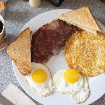 Steak and eggs with toast, hash browns and a cup of coffee.