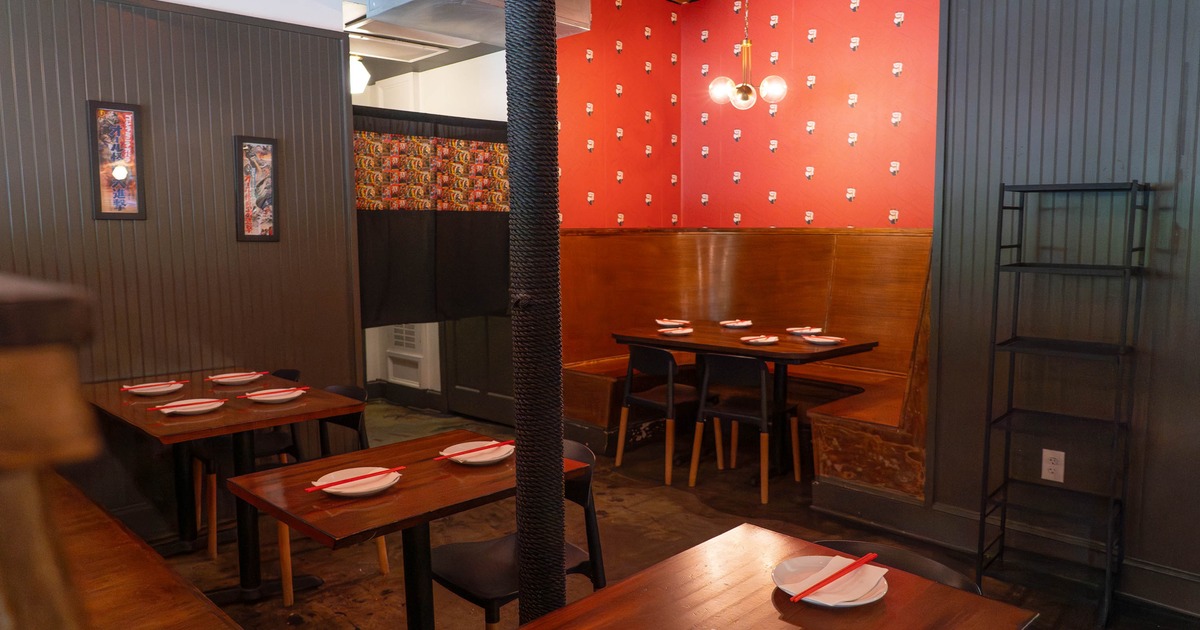 A restaurant interior with wooden tables, red wall with a booth