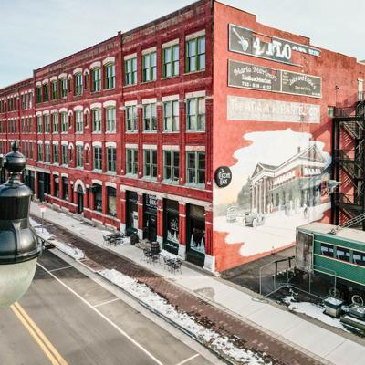The exterior, a red brick building with large windows and a mural on the side.