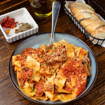 Pappardelle bolognese pasta with side bread.