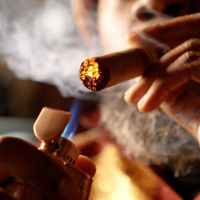 A person lighting a cigar.