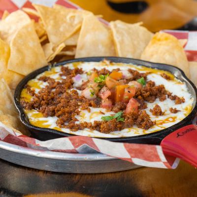 Cheese dip served in a skillet with a side of tortilla chips.