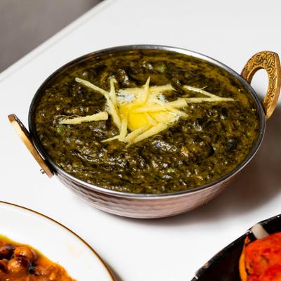 Saag curry garnished with butter and ginger strips.