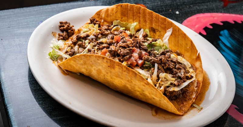 Crunchy taco with beef, lettuce, tomatoes, chili, and cheese
