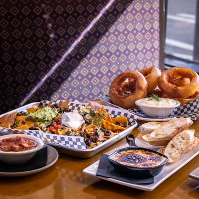 Nacho platter served with onion rings, garlic bread, and creamy dips.