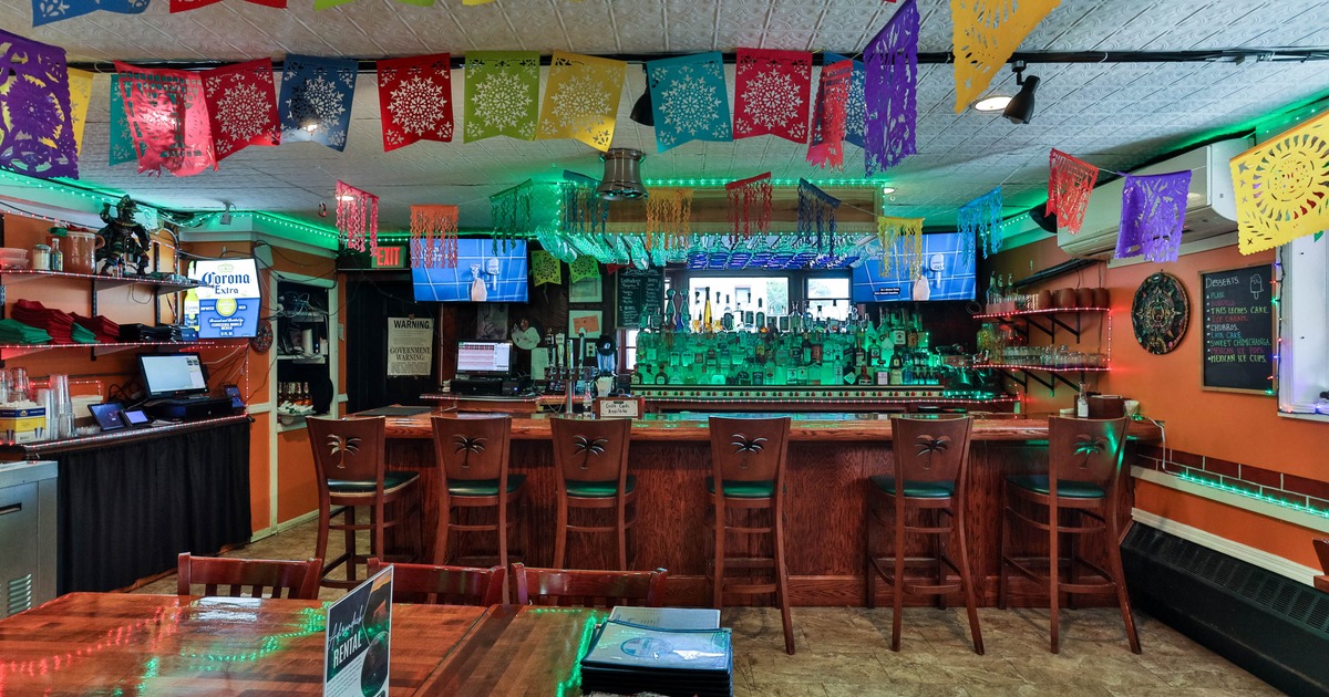 Interior, bar area, wooden top bar with stools, drink shelf in the back, Mexican motif decoration