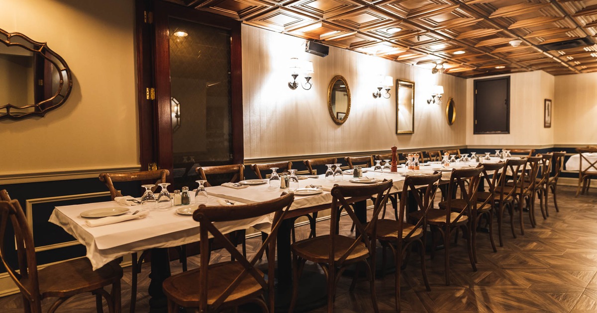 Interior, long table setup with chairs, ready for guests, lanterns on the wall