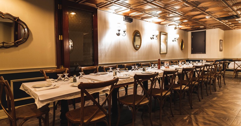 Interior, long table setup with chairs, ready for guests, lanterns on the wall