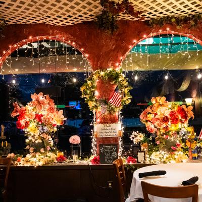 Restaurant interior with arches, lush flower arrangements, and string lights.
