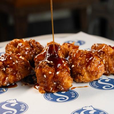 Sticky honey soy chicken with sesame seeds and sauce drizzling.