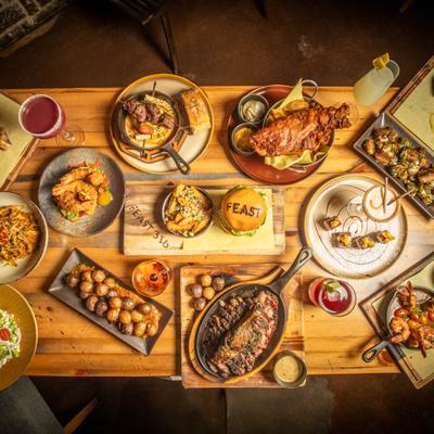Overhead view of a wooden table spread with a variety of dishes and drinks.