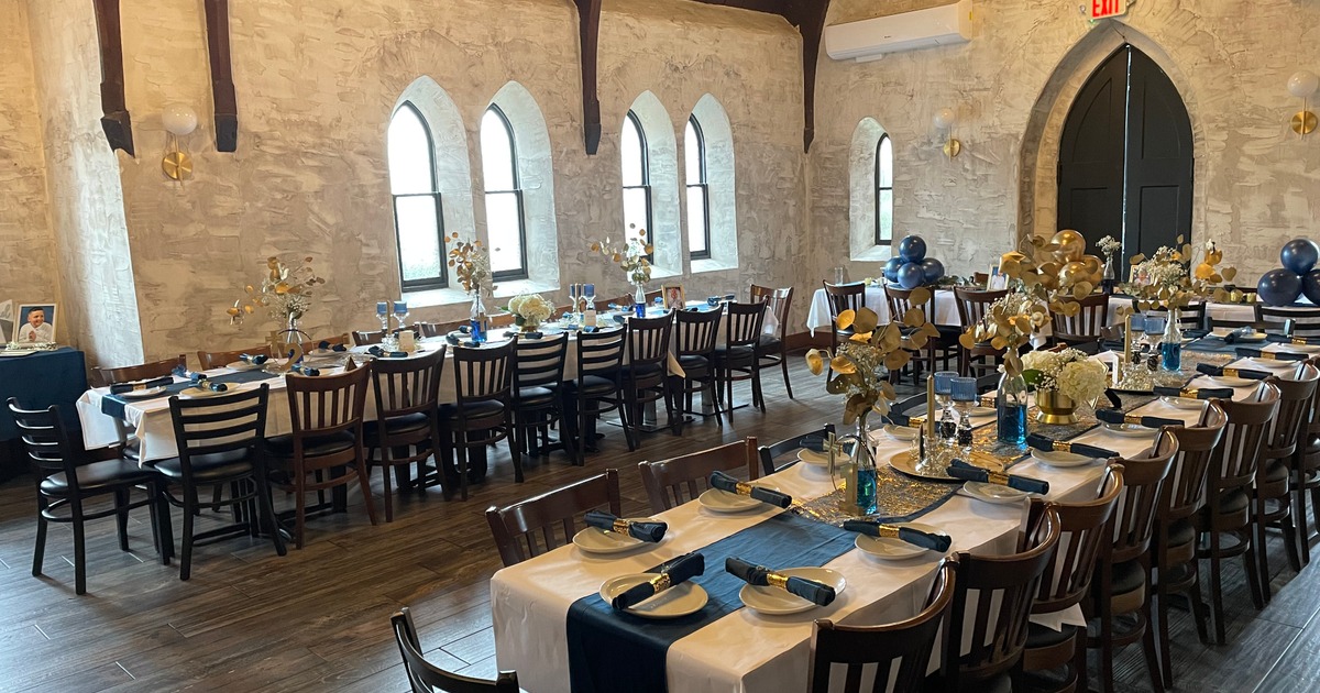 A spacious room arranged with tables and chairs, elegantly set up for a celebration