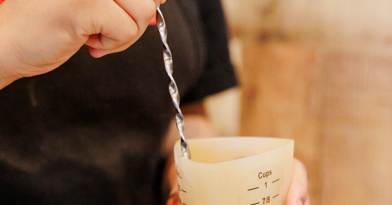 Person stirring liquid in a measuring cup