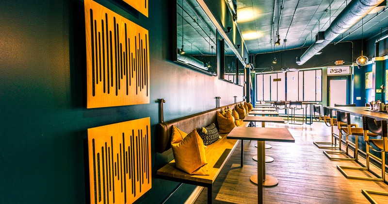 Interior, lined up tables and wall banquette seating  near the bar