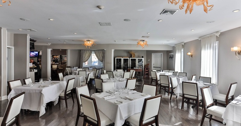 Elegant restaurant interior with white tablecloths, upholstered chairs, and orange light fixtures