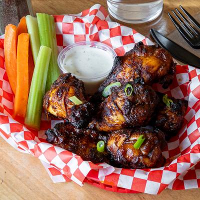 Smoked Chicken Wings served with sauce and veggies.