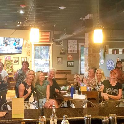 People at the bar, seating at tables and posing for a photo.