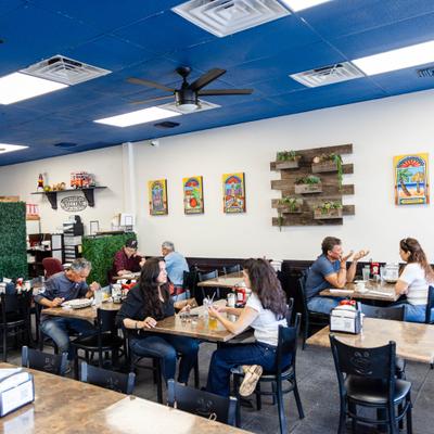Patrons sitting in a casual dining area with light-colored walls and a vibrant blue ceiling.