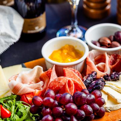 Vibrant charcuterie board with cured meats, cheeses, grapes, olives, and bright fruit spread.