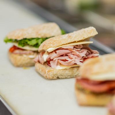 Various sandwiches served on a ciabatta rolls on a kitchen counter.