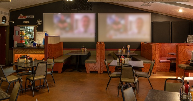 Diner area, tables, chairs, booths behind,  video beam screens above