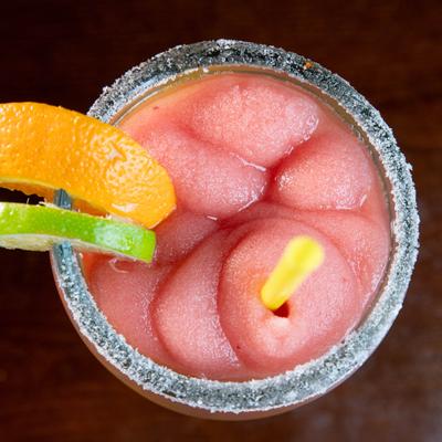 Frozen Strawberry Margarita served in a salt-rimmed glass with citrus slices.