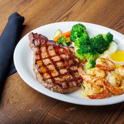Grilled steak with shrimp, rice, and vegetables.