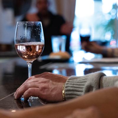 Close up shot of bar counter, customer's hands with a served glass of  white wine.