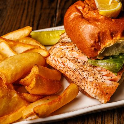 Salmon BLT sandwich with crispy potatoes.