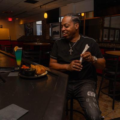 Person having food and a cocktail at the bar.