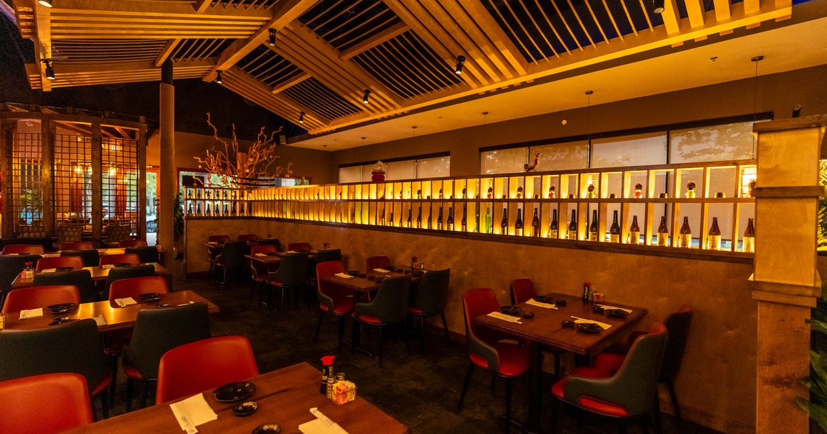 Dining area featuring a long back-lit wall shelf displaying numerous bottles