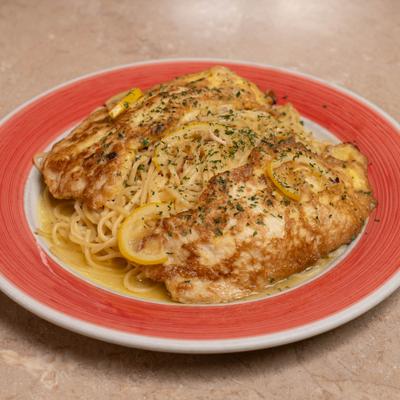 Chicken topped with lemon slices, served over pasta.