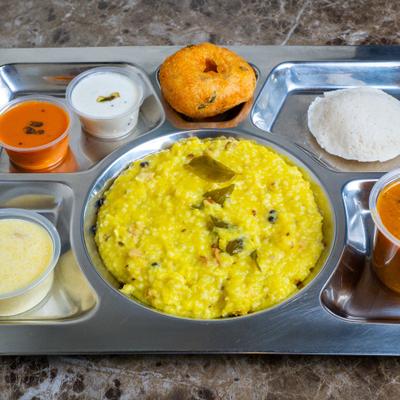 A platter with a yellow lentil dish served with various chutneys.